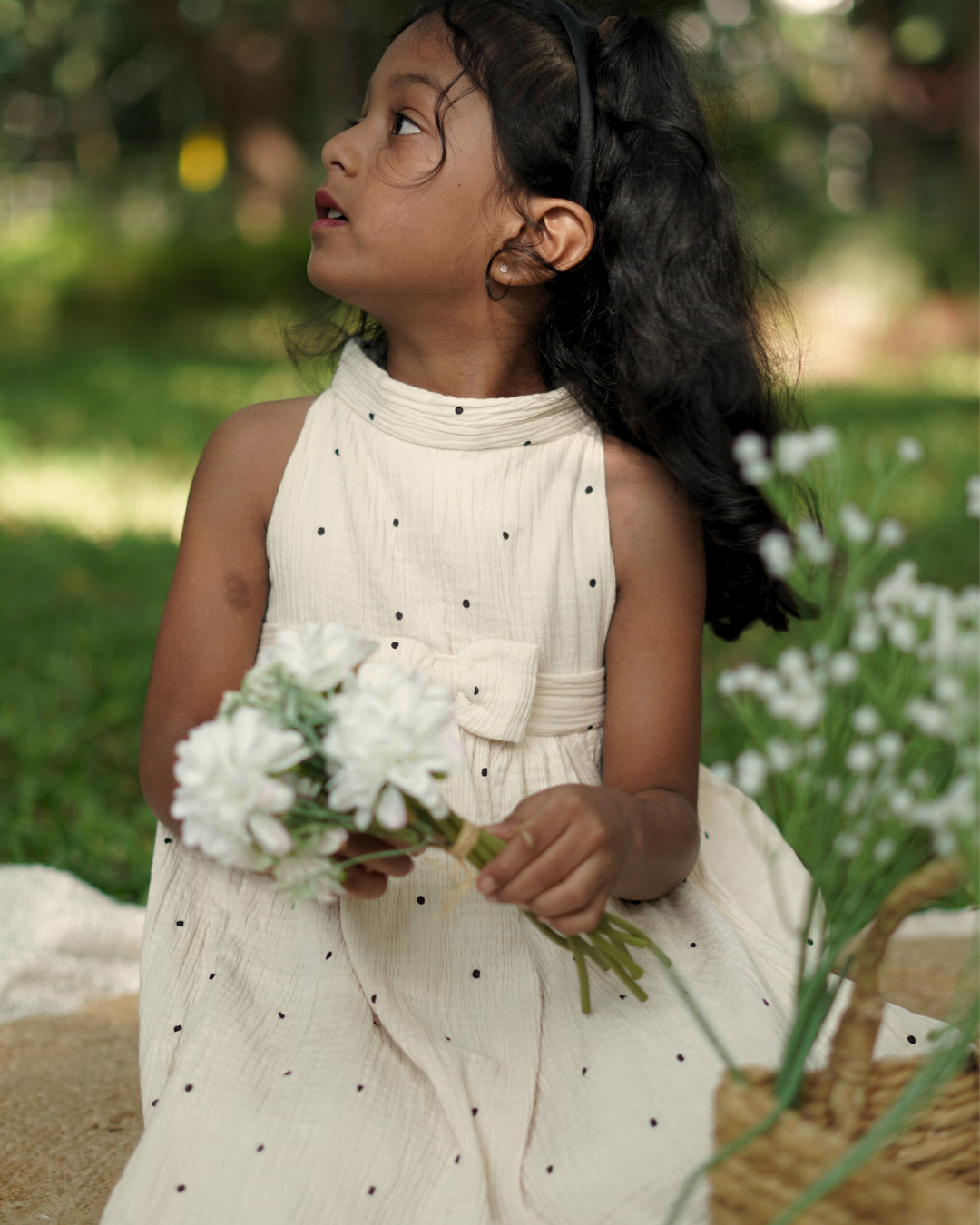 Young girl wearing the Faye Cream Polka High Neck dress outdoors in a grassy area