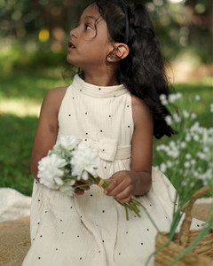 Young girl wearing the Faye Cream Polka High Neck dress outdoors in a grassy area