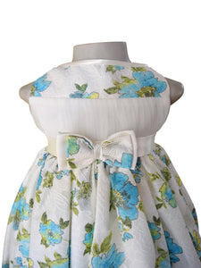 A baby girls dress from Faye in blue pastel printed floral Lace with satin sash  and double bow.