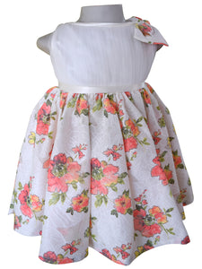 A sleeveless baby girl's dress. The dress features an off white net bodice, a  satin waistband, and a skirt with a vibrant watercolor-style floral print in coral & green
