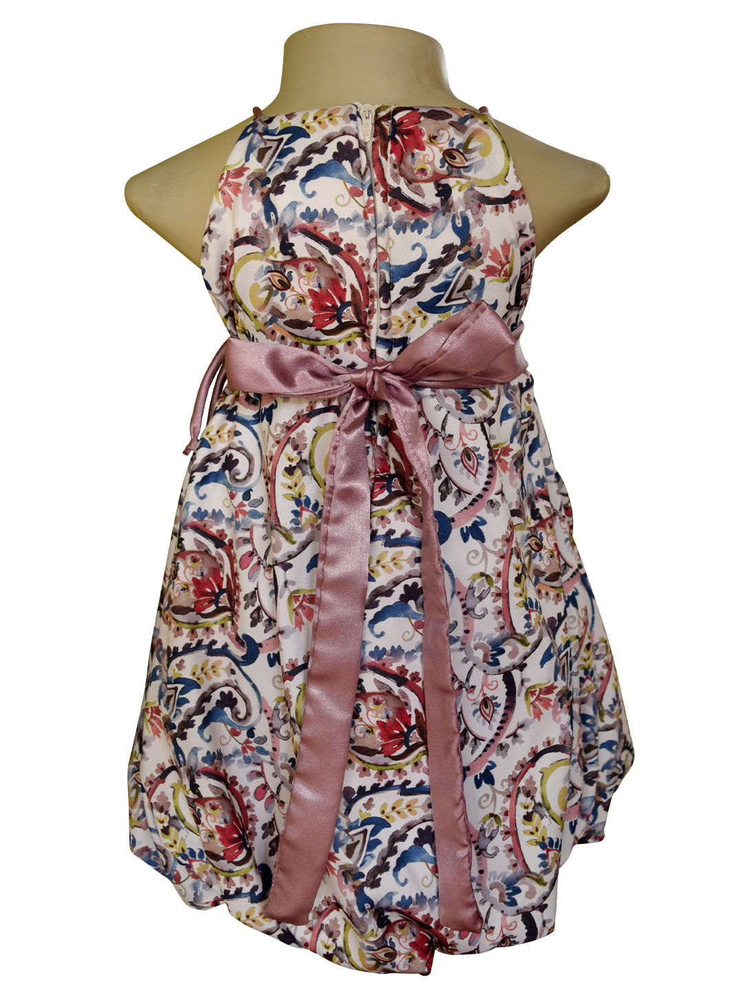 A sleeveless halter dress displayed on a mannequin torso against a white background. The dress features a colorful paisley and floral pattern on a light base with a dusty pink satin waist tie and bow.
