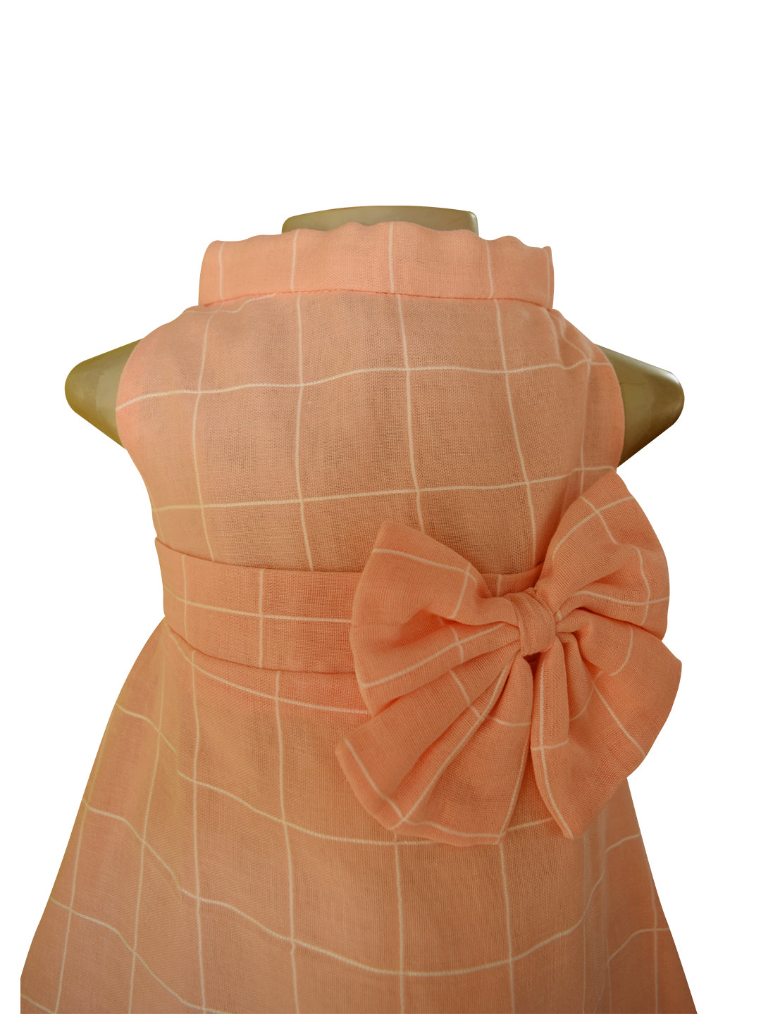 A peach high neck dress with cream checks and bows at the waist. 