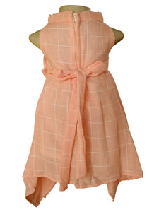 Back side view of a sleeveless peach-colored dress displayed on a mannequin torso against a white background. The dress features a white windowpane plaid pattern, a high mock neck, a tie belt at the waist, and an asymmetrical hem.