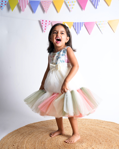 Young girl in the Faye Embroidered Tiered Multi-coloured Pastel Dress standing on a woven mat.