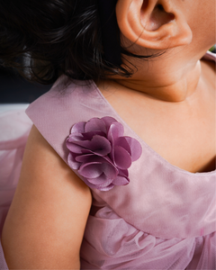 Close-up of a child wearing the Faye Taupe Swing Dress with flower detail.